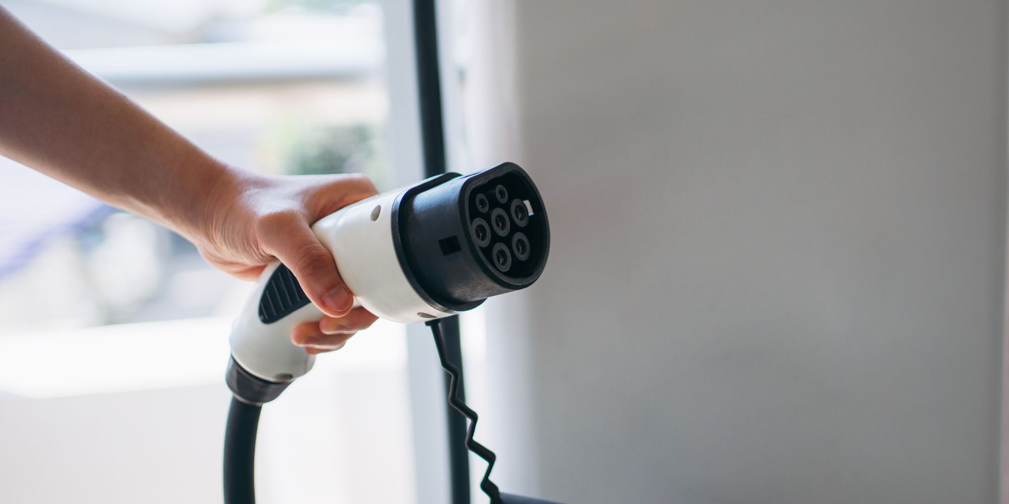 Hand holding a Level 2 EV charging connector